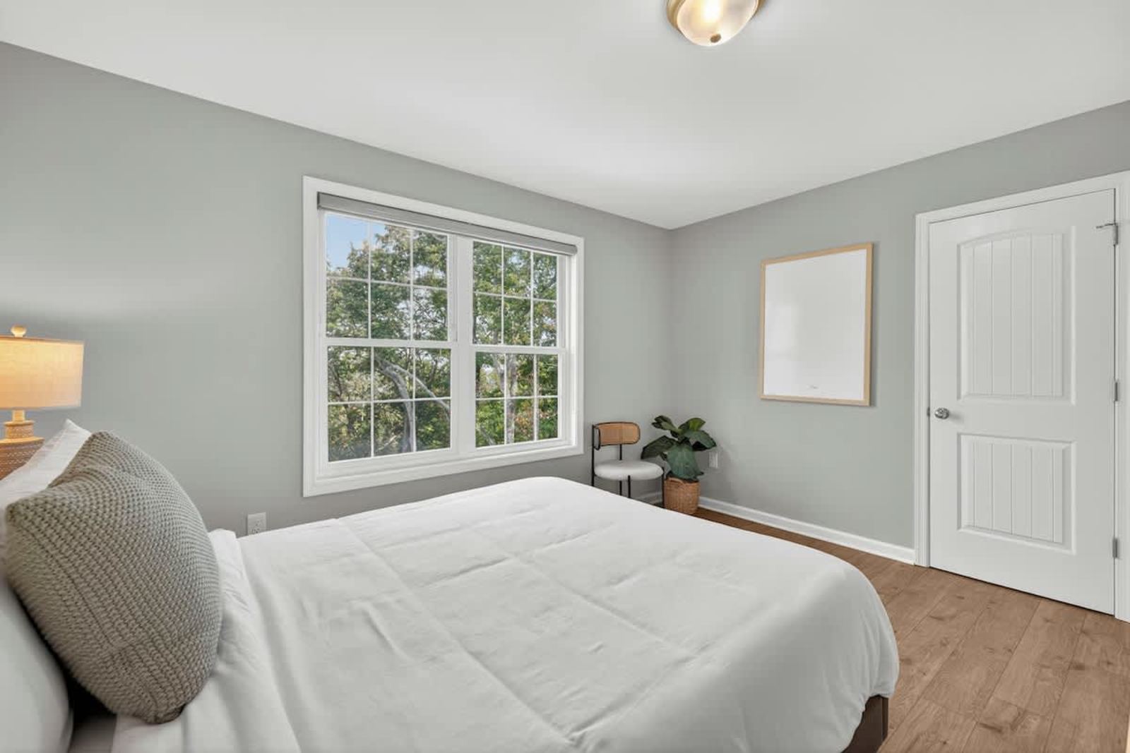 Queen guest bedroom with a leafy treetop window view